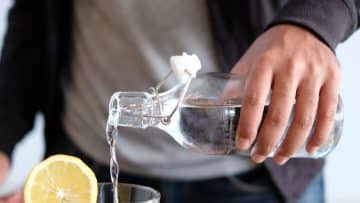 man pouring water in glass